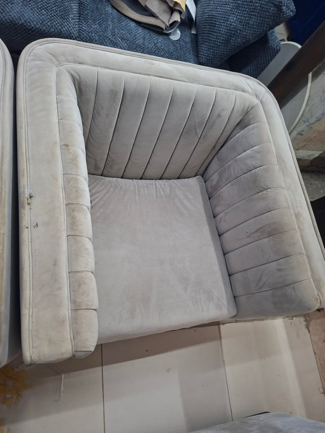 Close-up top view of used grey channel-tufted accent armchair seat and armrest condition