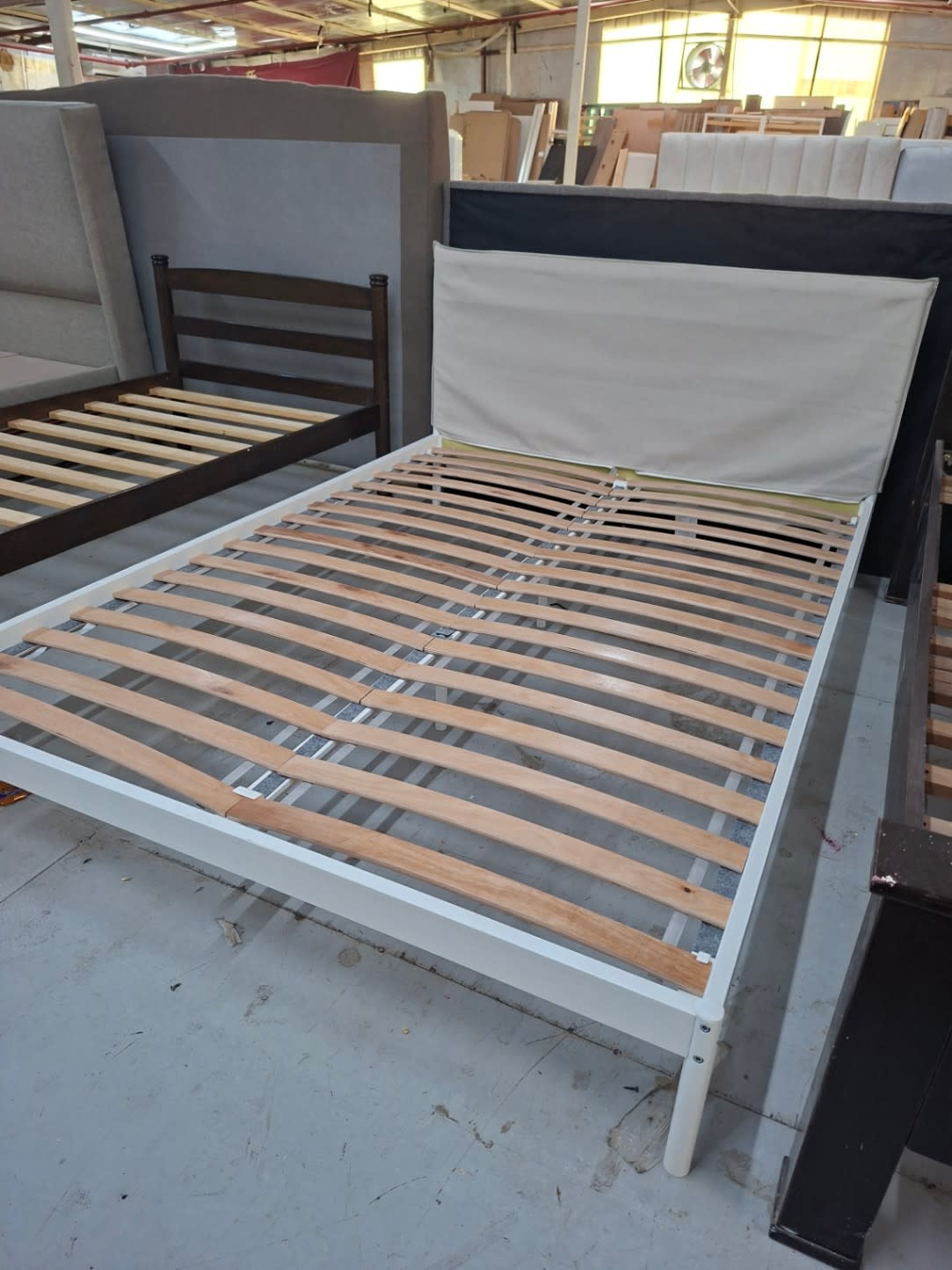 Side angle of used white metal queen bed frame with upholstered headboard at Shop E Ajman