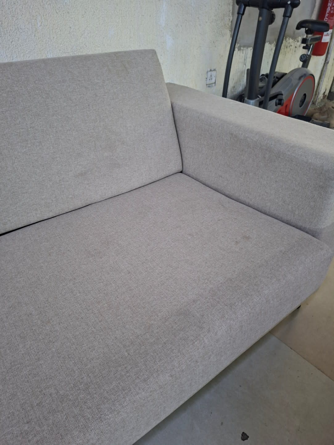 Close-up of armrest and seat area of used beige 2-seater fabric sofa at Bufaisal Ajman