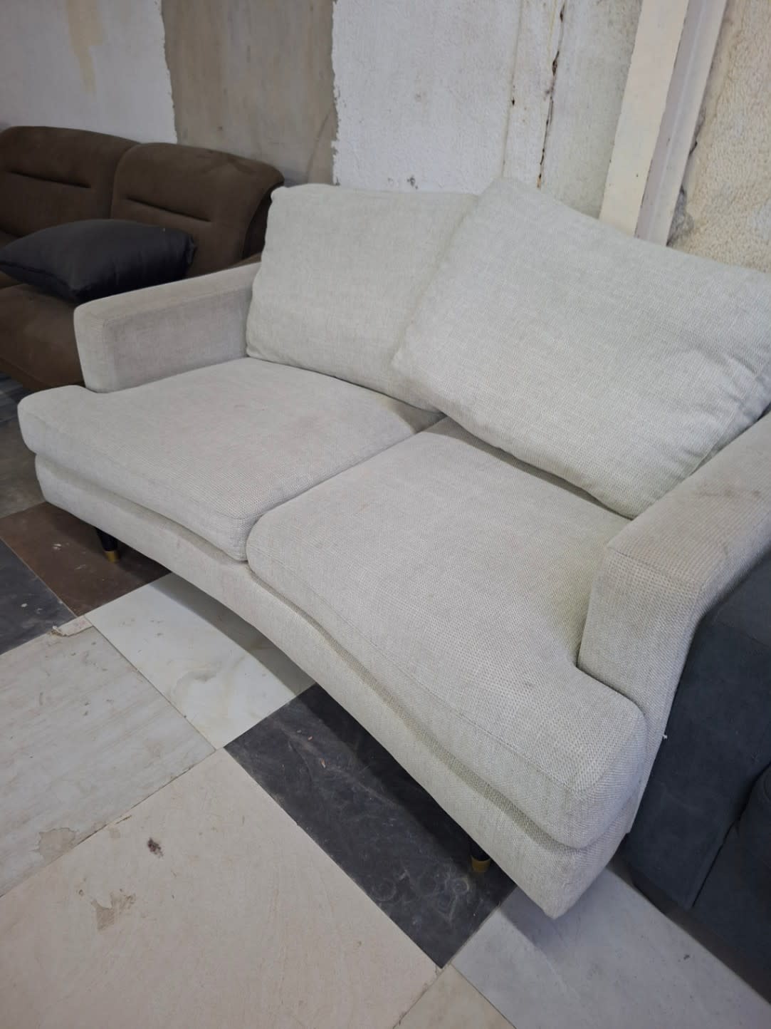 Side angle view of used beige 2-seater fabric sofa showing legs and overall structure at Bufaisal Ajman
