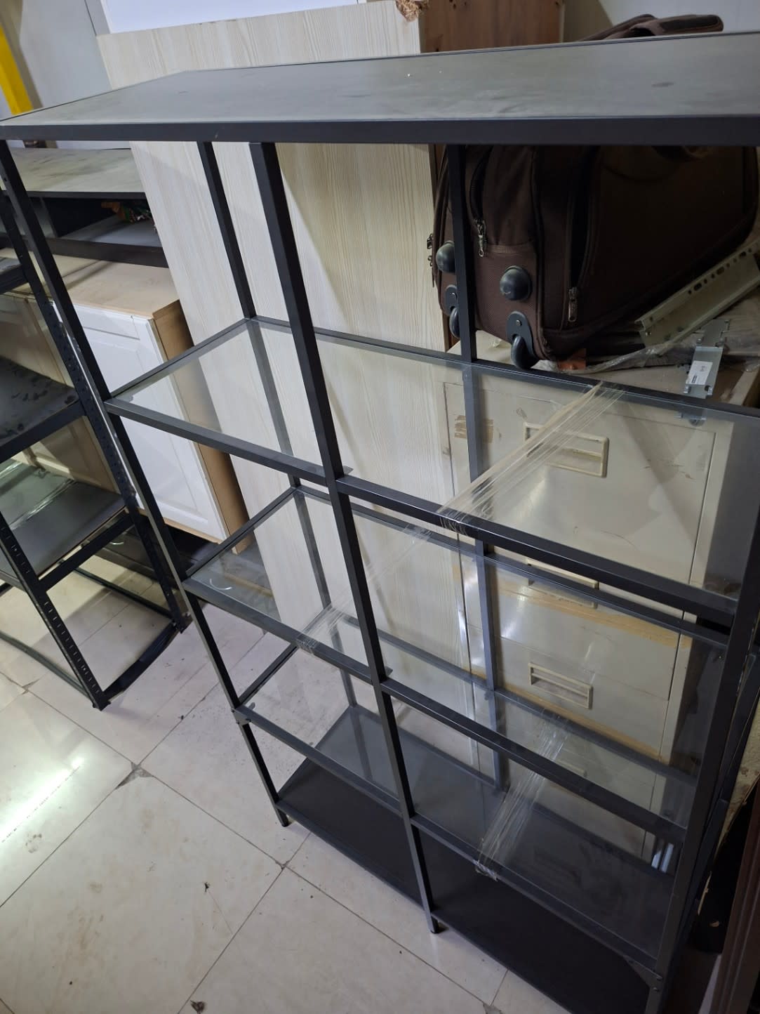 Top-down angled view of used black metal glass shelving unit showing frame and shelf surface condition