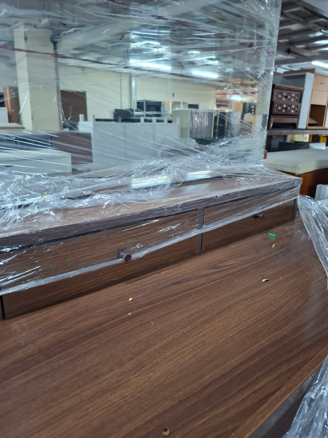 Close-up of used dressing table drawers and walnut-finish surface with protective wrapping at Bufaisal Ajman