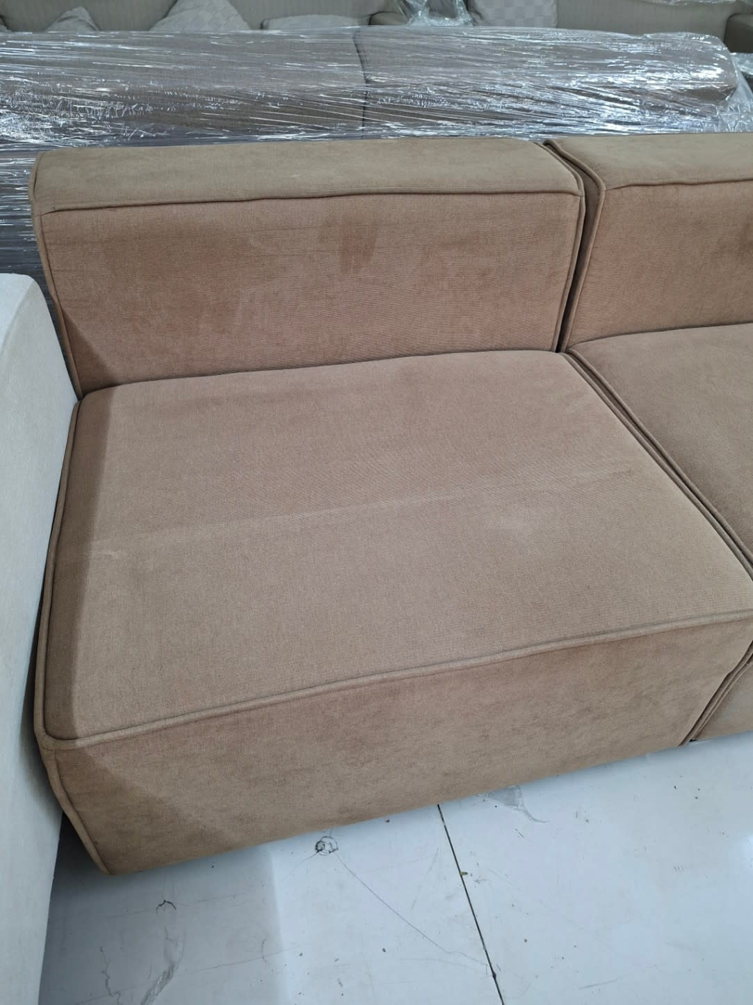 Close-up of used beige modular sectional sofa seat cushions showing light surface soiling at Bufaisal Ajman