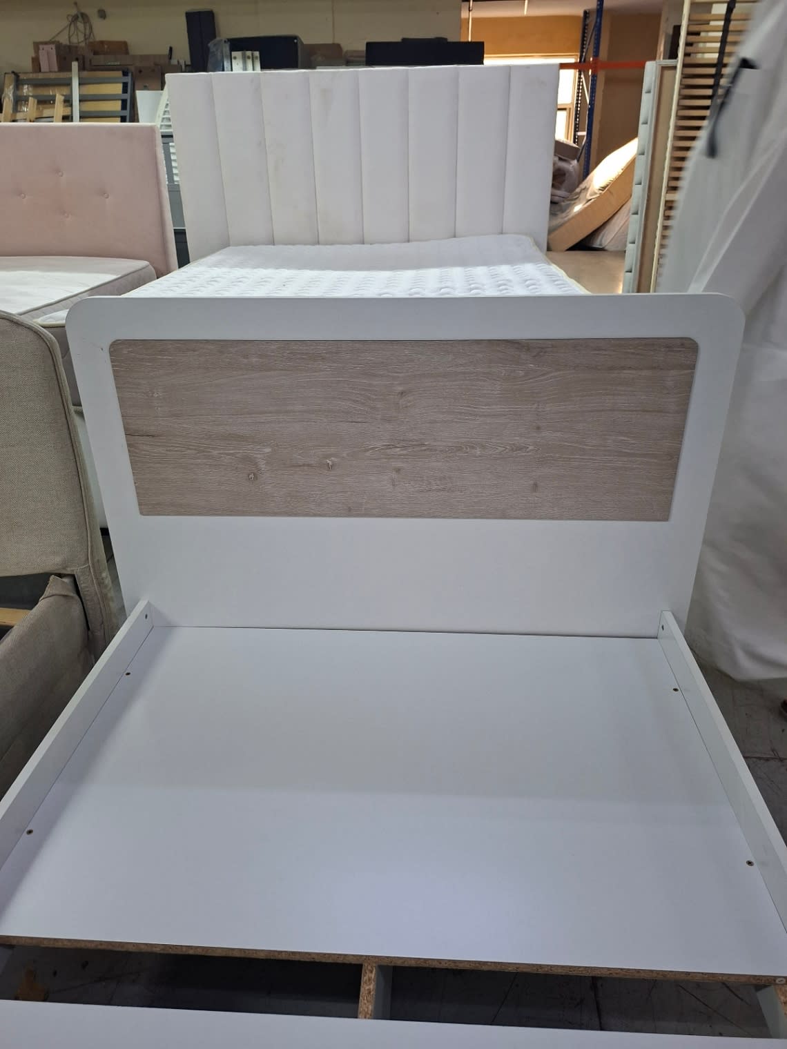 Close-up of used single bed frame headboard with oak-effect wood panel insert at Bufaisal Shop C Ajman