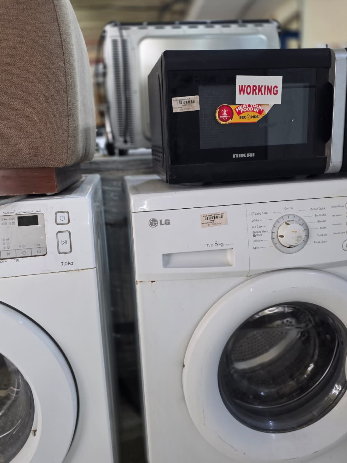 Bufaisal barcode label on used LG 5kg front-load washing machine at Shop C Ajman