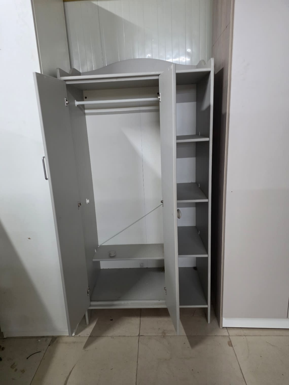 Interior detail of used grey 2-door wardrobe with hanging rail and 5-shelf side unit at Bufaisal Ajman
