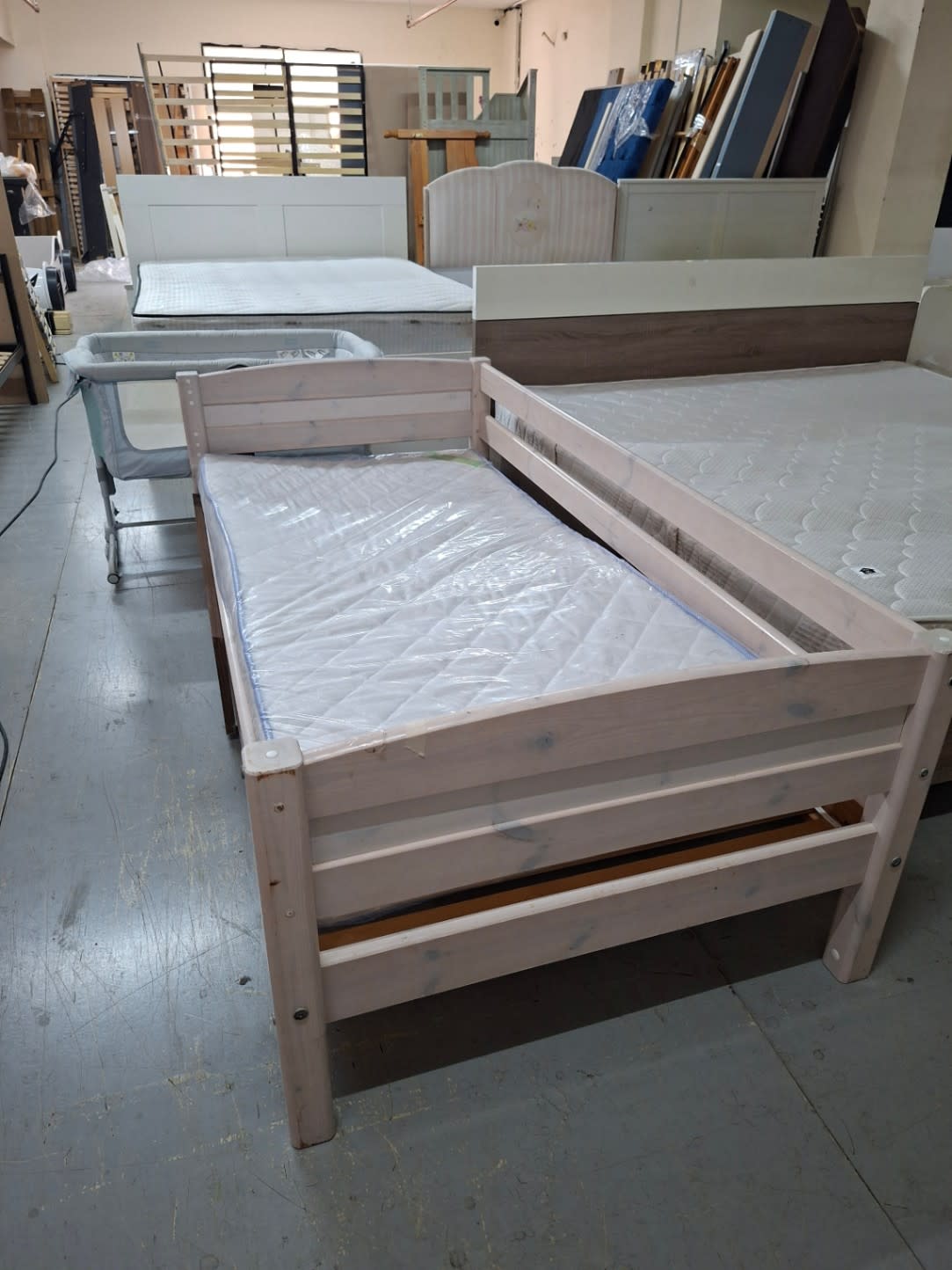 Side angle of used single kids bed frame showing whitewash wood finish and corner post detail