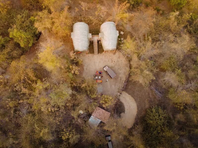 Drone aerial photograph of Limban's two Wilderness Pods set within dense tree cover, their curved forms visible from directly above, surrounded by a canopy of forest.