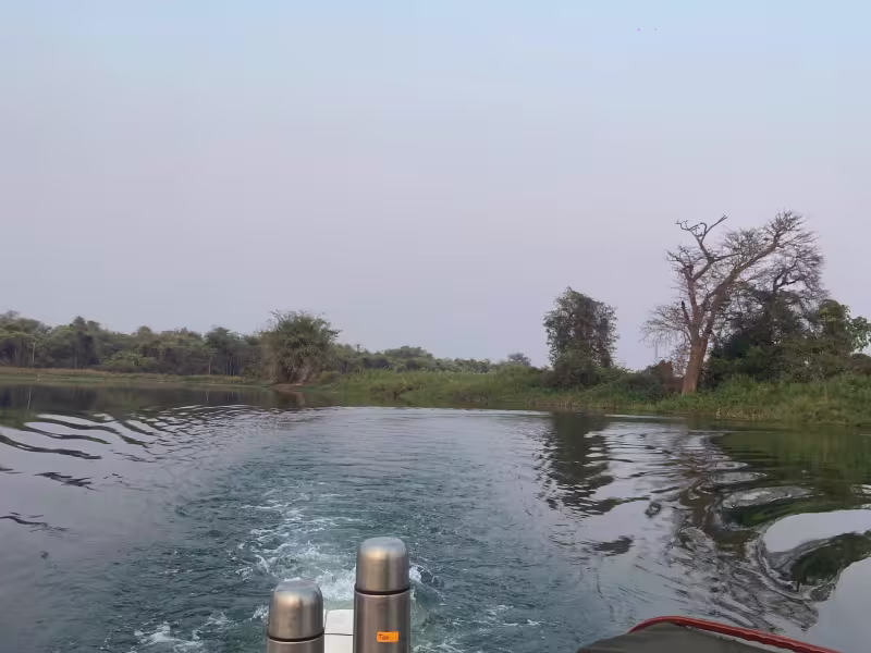 Guests on a boat tour on Irai Lake near Tadoba, surrounded by calm water reflecting the sky, with forest and wilderness visible along the distant shoreline.