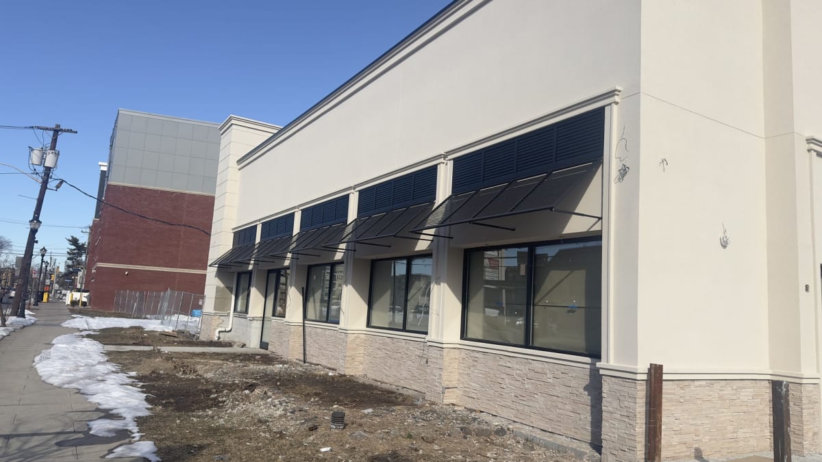Dark-finish aluminum storefront windows along the Teaneck building exterior
