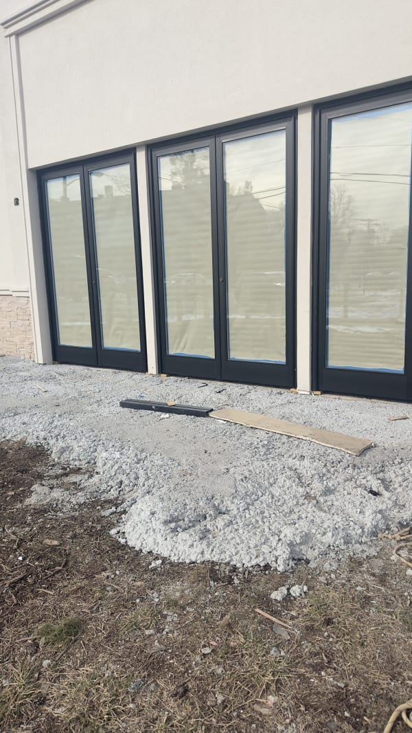 Paired dark-framed glass entrance doors at the Teaneck project during construction