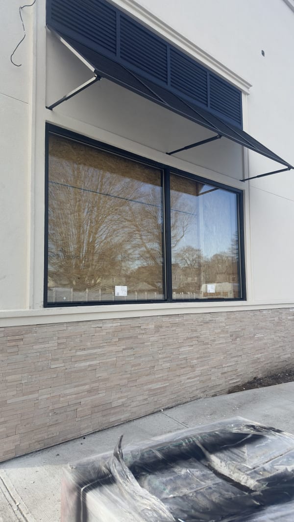 Storefront window framing and glass beneath an exterior awning