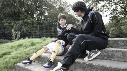 Durch positiv-konstruktiv formulierte Kritik wird der Spieler besser und geht mit einem guten Gefühl aus dem Gespräch © 2019 Philippka-Sportverlag Ein Trainer und sein Spieler sitzen auf einer Treppe, gucken sich gegenseitig ins Gesicht und geben sich die Hand. Hier hat ein konstruktives Gespräch stattgefunden. © 2019 Philippka-Sportverlag