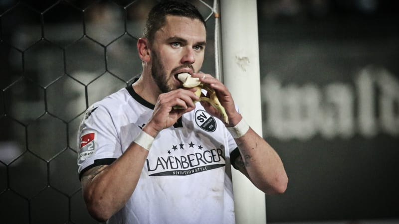 Pascal Testroet vom SV Sandhausen isst während des Spiels eine Banane. © 2021 IMAGO / Jan Huebner Pascal Testroet vom SV Sandhausen isst während des Spiels eine Banane.