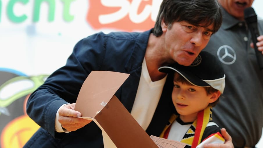 Joachim Löw mit einem kleinen Fan bei einem Schulbesuch Bundestrainer Joachim Loew umarmt einen junge Fußballfan während eines Schulbesuchs. (Photo by Dennis Grombkowski/Bongarts/Getty Images)