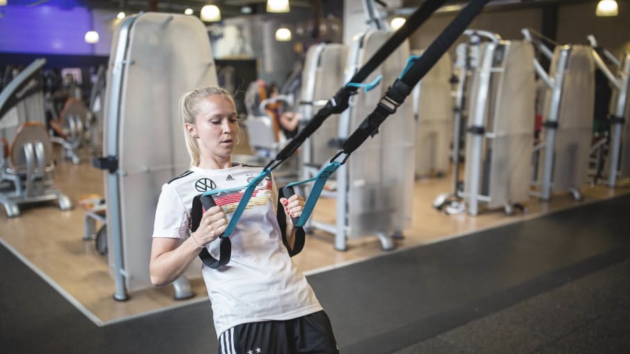Turid Knaak an einem Fitnessgerät © 2019 Getty Images Nationalspielerin Turdi Kraak trainiert während der FIFA-Frauen-WM 2019 an einem Gerät in einem Fitnessraum.