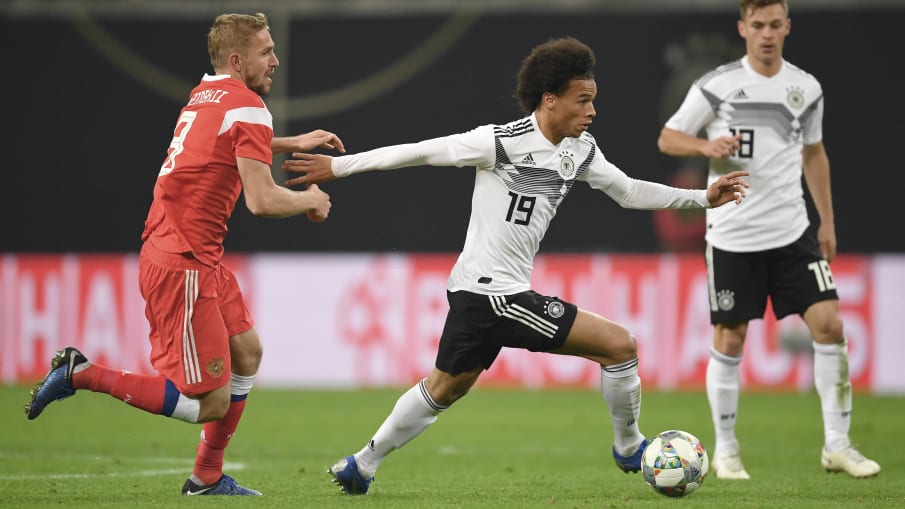 Leroy Sané läuft einem Gegenspieler davon © 2018 Getty Images Leroy Sané (Deutschland) wird von Juri Gasinski (Russland) in einem Testspiel angegriffen.