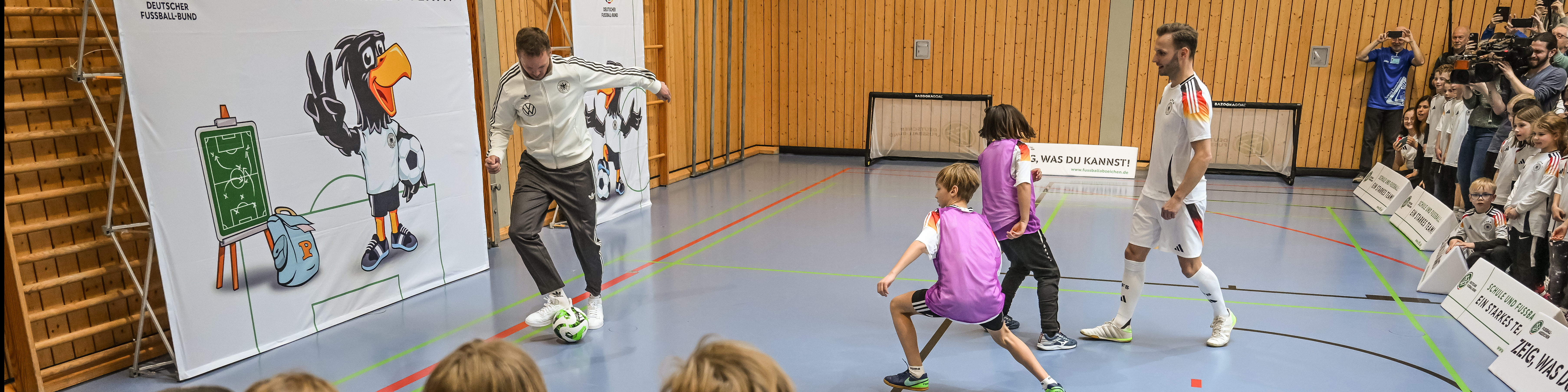 DFB Delegation Visits Local School MAINZ, GERMANY - MARCH 18: Julian Nagelsmann, Head coach of Germany plays with Adrian Fogel, freestyler against 2 kids football during a Delegation visit from Julian Nagelsmann, Head coach Germany, Rudi Voeller, Managing director Sport and Andreas Rettig, Manager of DFB at the elementary school Essenheim on March 18, 2024 in Mainz, Germany. (Photo by Christian Kaspar-Bartke/Getty Images for DFB)