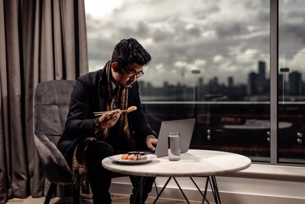 A business traveller working and eating dinner in his Roomzzz apartment.