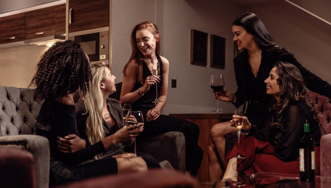 A group of women drinking together in their serviced apartment at Roomzzz.