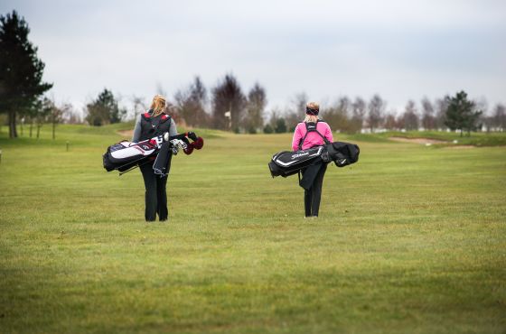 Ellie and golfer walking on the green at Leeds Golf Centre