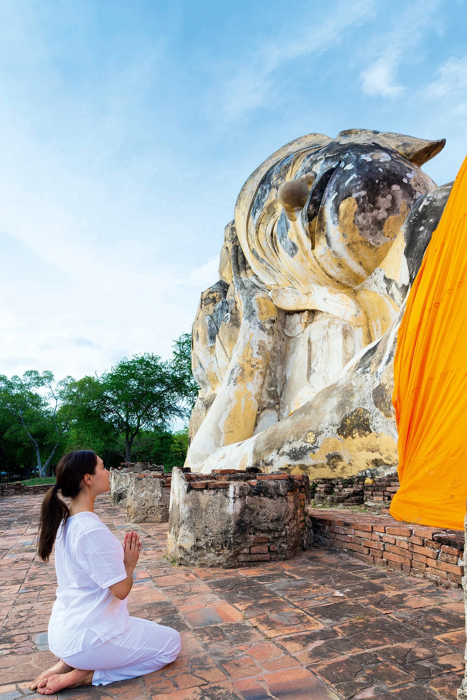 Woman kneeling in front of buddha statue