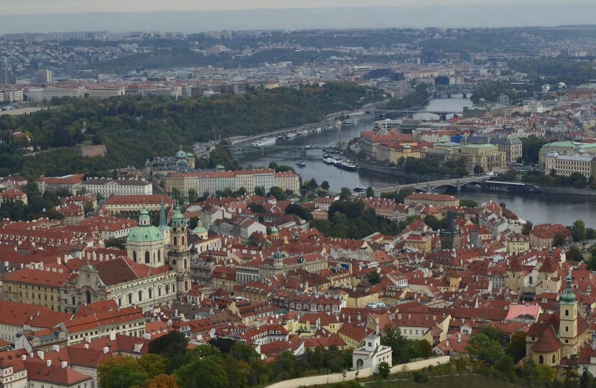 Panorámica de la ciudad de Praga desde un mirador, con el río Moldava y sus puentes al amanecer.