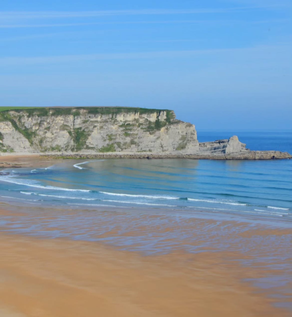Playa de arena en Santander con acantilados rocosos