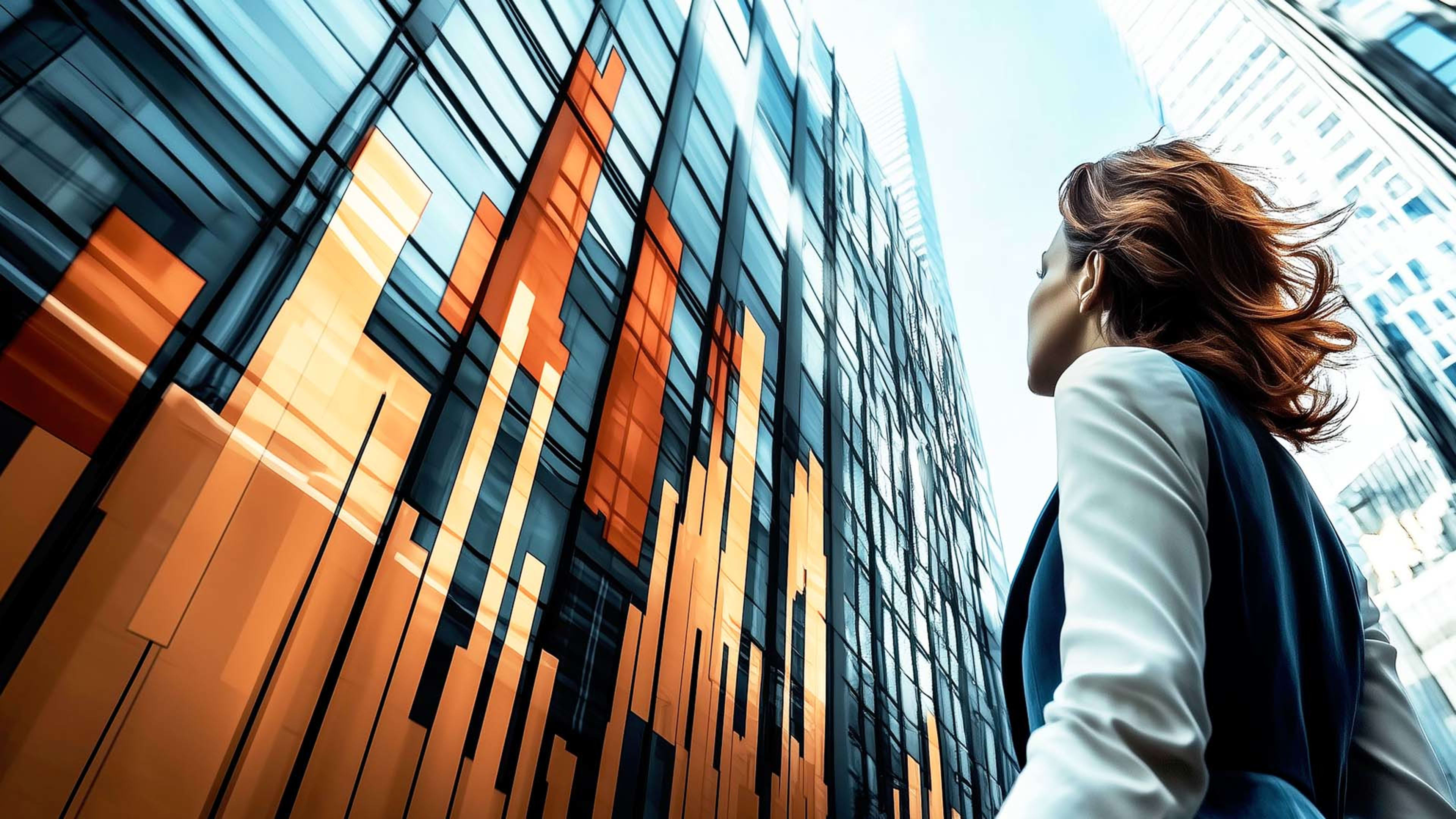 A person with long, flowing hair stands in front of a modern, multi-colored glass building.