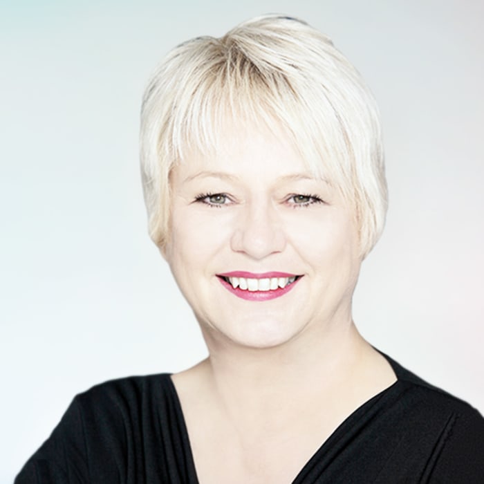 A smiling woman with blonde hair against a light blue background.