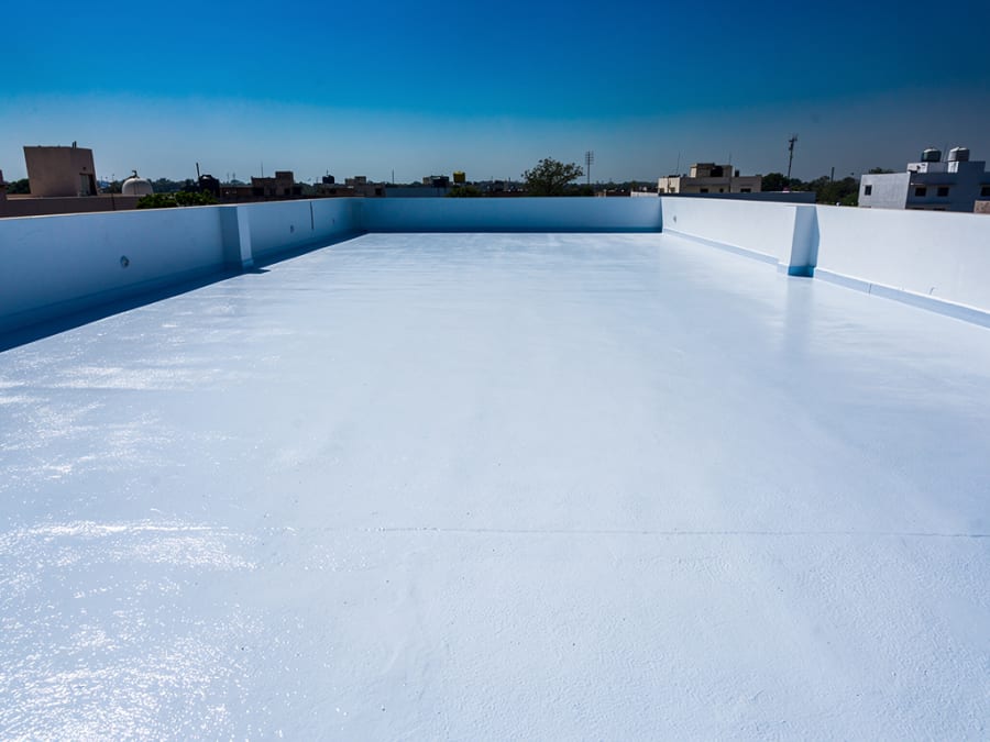 Flat rooftop terrace finished with reflective cool-roof coating under strong sun