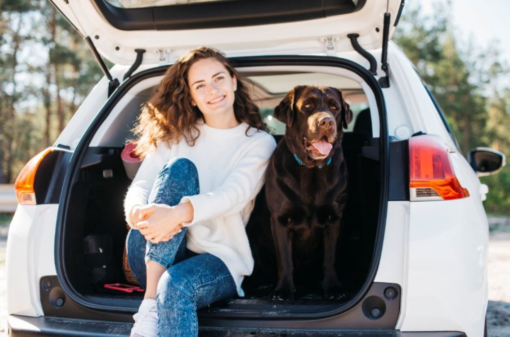young-girl-seating-in-the-trunk-of-her-car-with-her-dog.jpeg