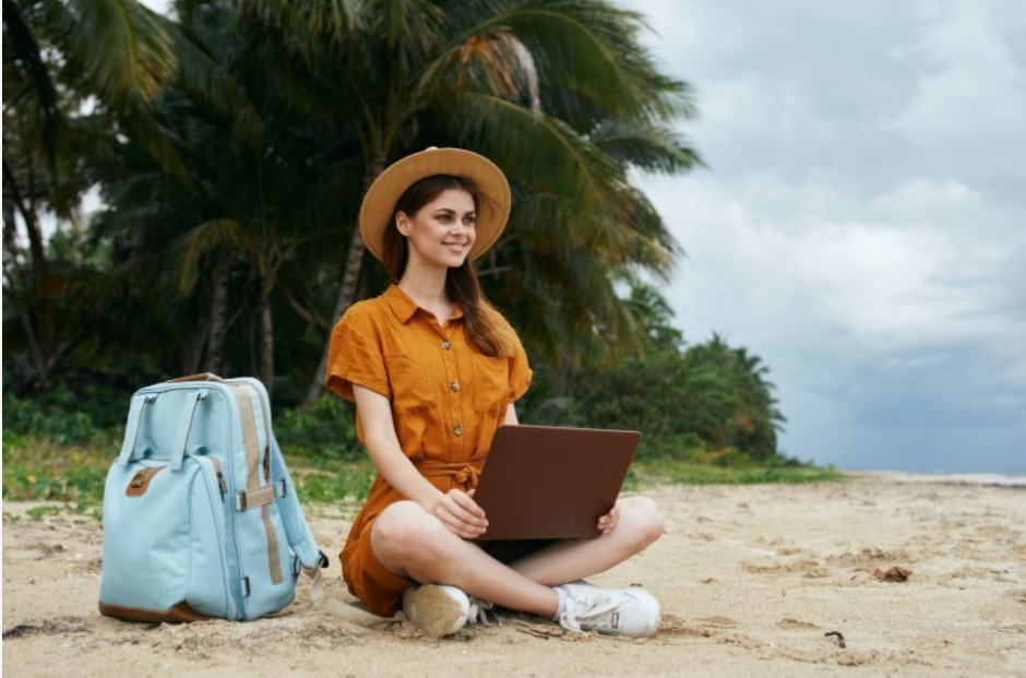 woman-seating-on-a-tropcial-beach-with-a-hat-and-a-backpack.jpeg