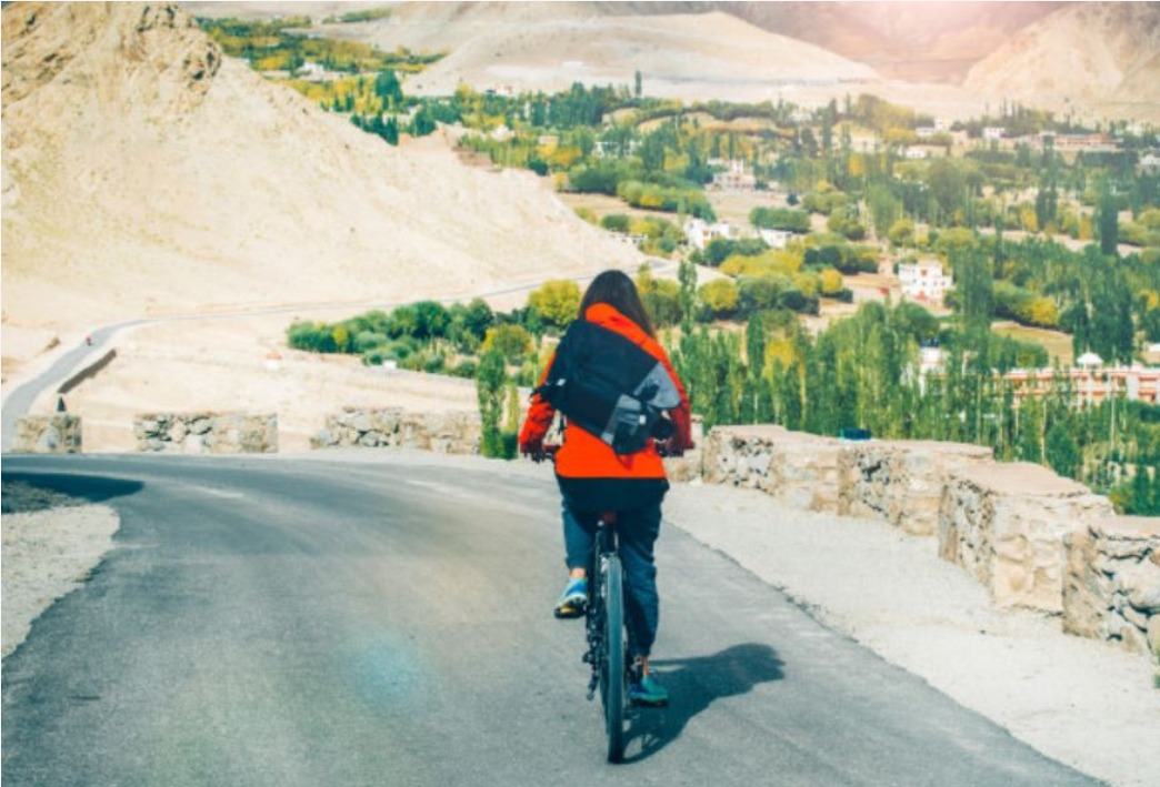 fahrradfahrerin-mit-rucksack-faehrt-auf-einer-landstrasse.jpeg