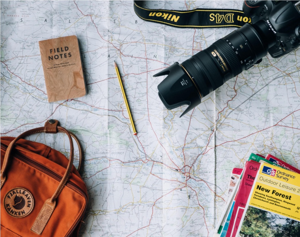 camera, pencil, notebook and backpack on a map .jpeg