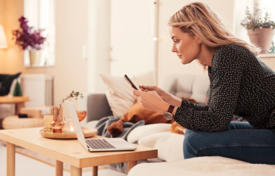 woman-seated-in-a-living-room-looking-at-her-laptop-and-phone.jpeg