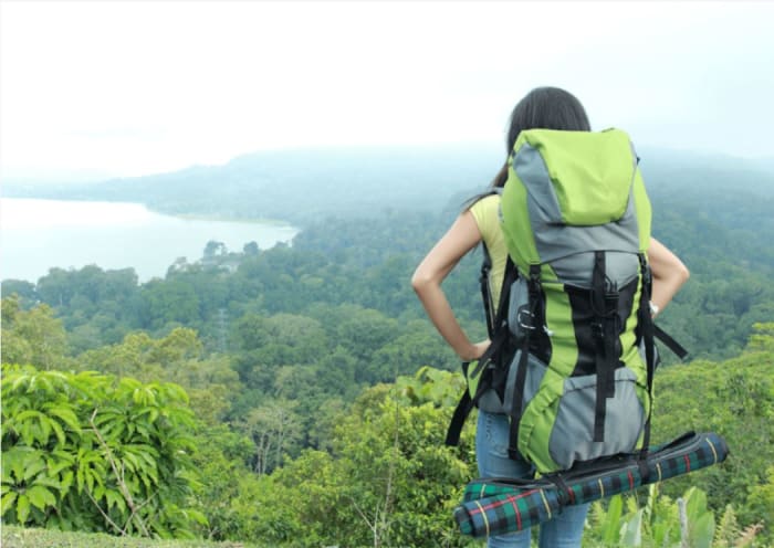 frau-mit-rucksack-und-isomatte-blickt-auf-ein-bewaldetes-tal-mit-einem-see.JPG