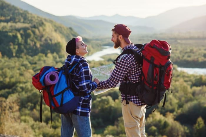 couple-holding-a-map-looking-at-each-other-in-nature-with-backpacks.jpeg