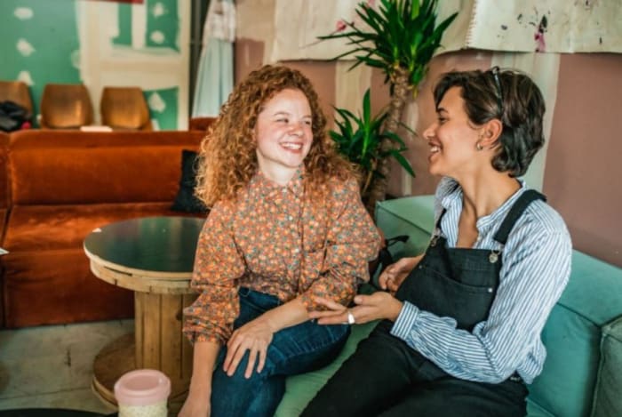 2 mujeres sentadas en un café y riendo juntas.jpeg