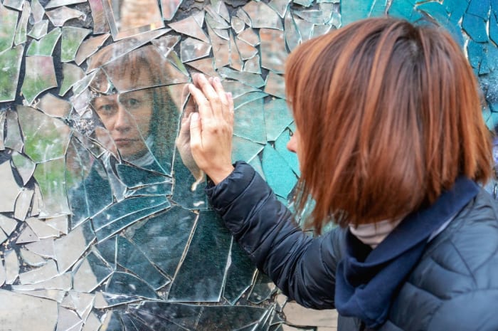 a-woman-with-her-reflection-in-a-broken-mirror.jpeg