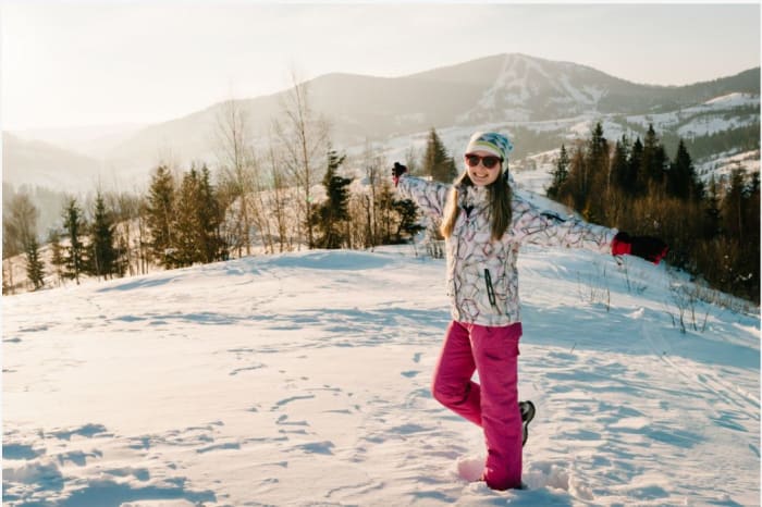urlaub-im-februar-frau-in-winterkleidung-steht-auf-einem-verschneiten-berg.JPG