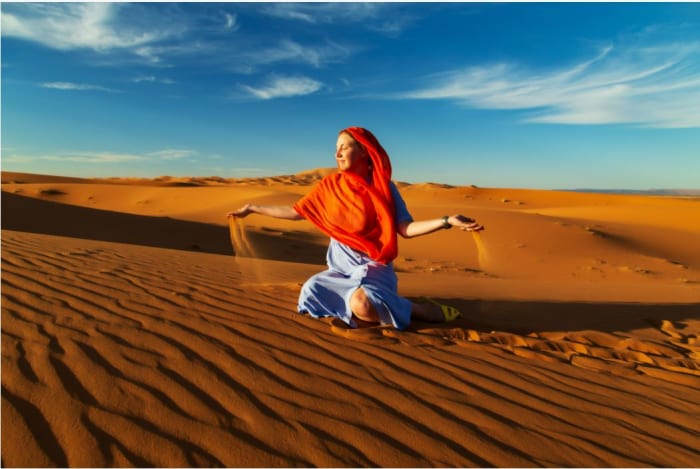 frau-spielt-mit-sand-in-wüste.JPG