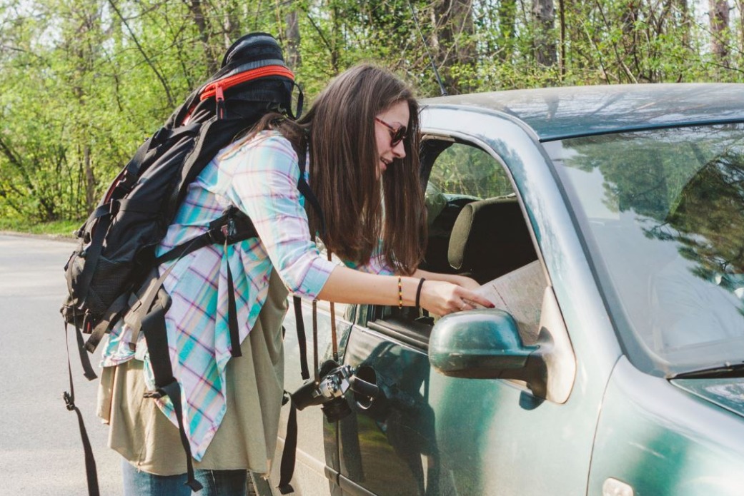 a-woman-with-a-backpack-showing-something-on-a-map-to-a-driver-in-his-car.jpeg