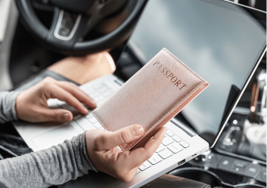 person-am-laptop-haelt-eine-reisepasshuelle-in-der-hand.JPG