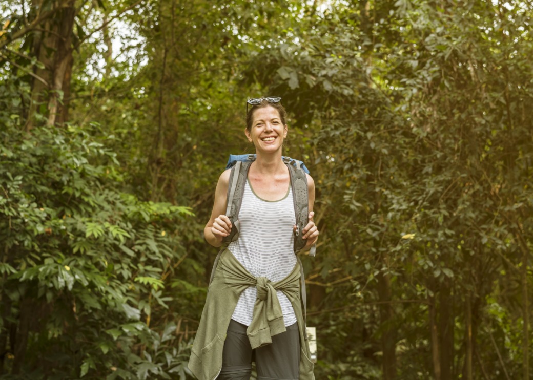 a-woman-in-nature-smiling-with-a-backpack.jpeg