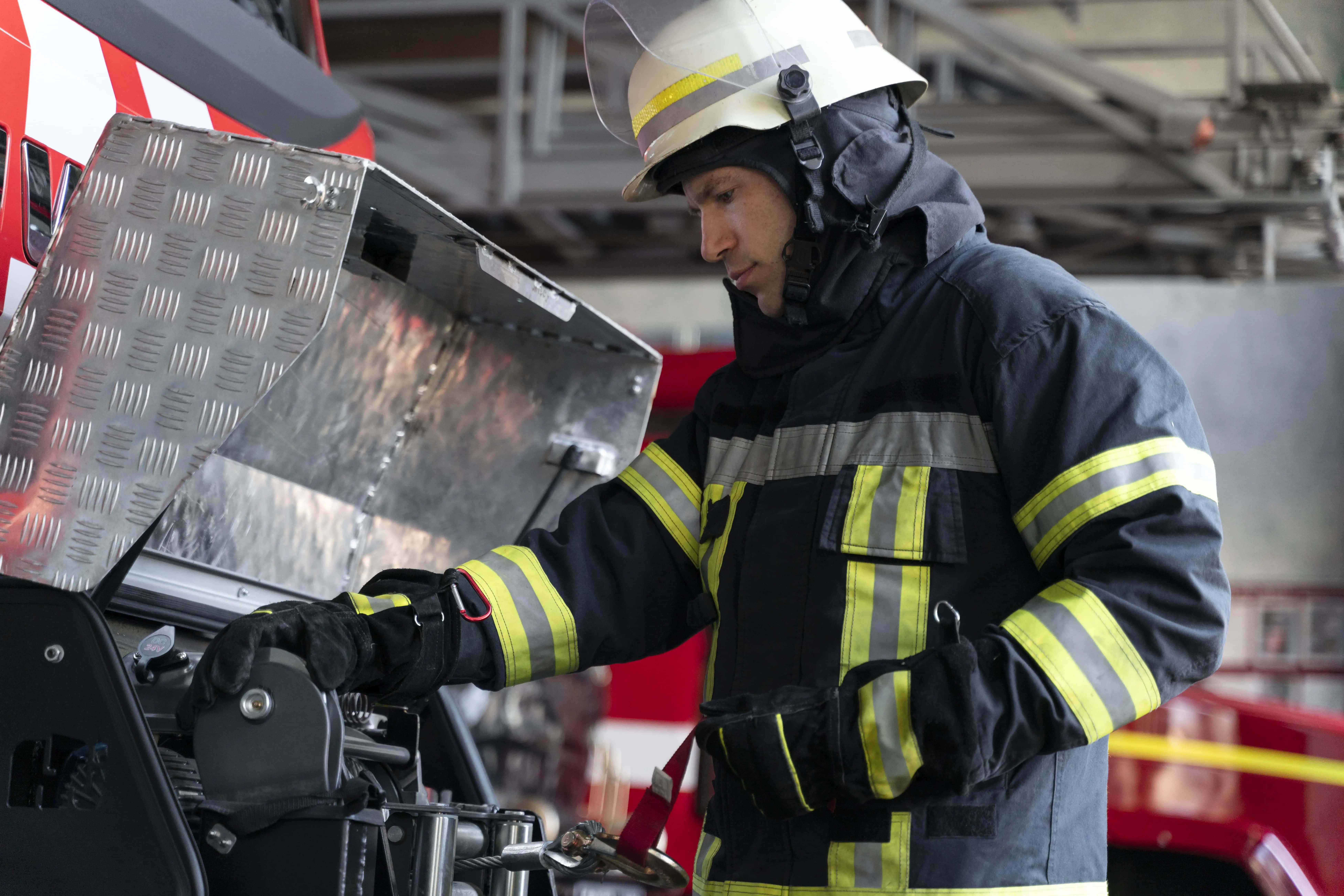 Firefighter in full gear standing near fire truck, representing emergency readiness
