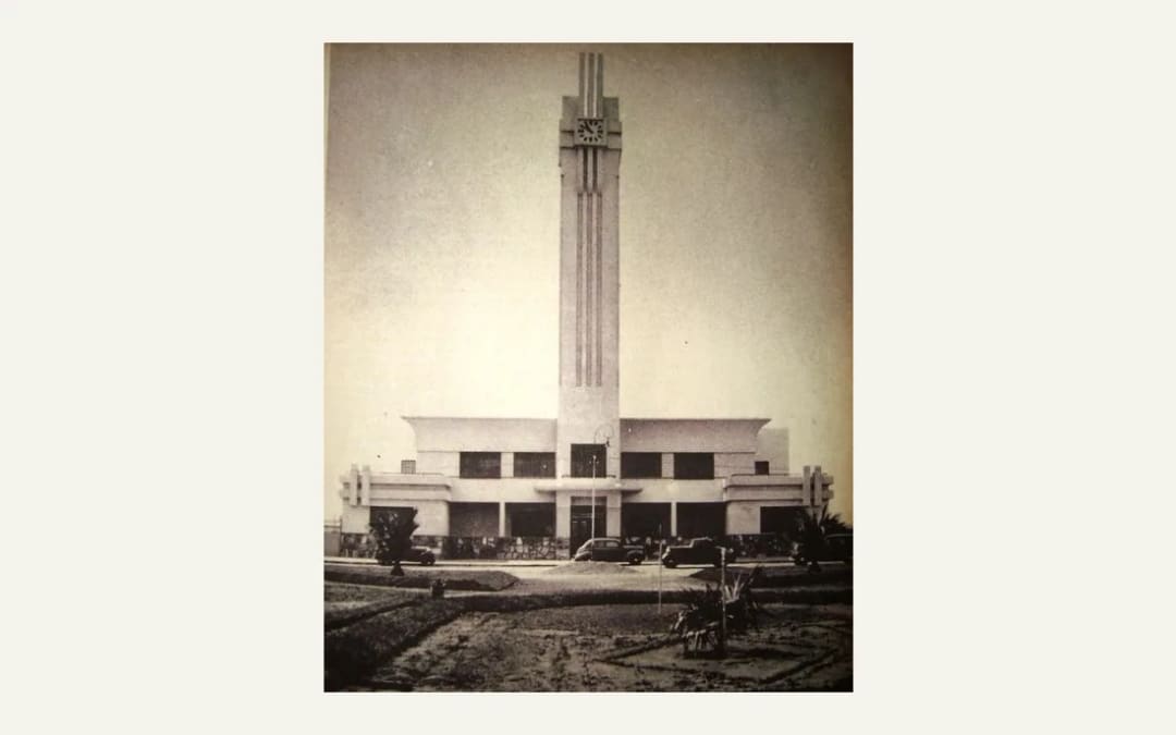 Fotografía de 1940 del Palacio Municipal de Tornquist: un edificio bajo de hormigón, simétrico, con una torre alta y estriada en el centro que lleva un reloj. Autos de la época estacionados al frente.