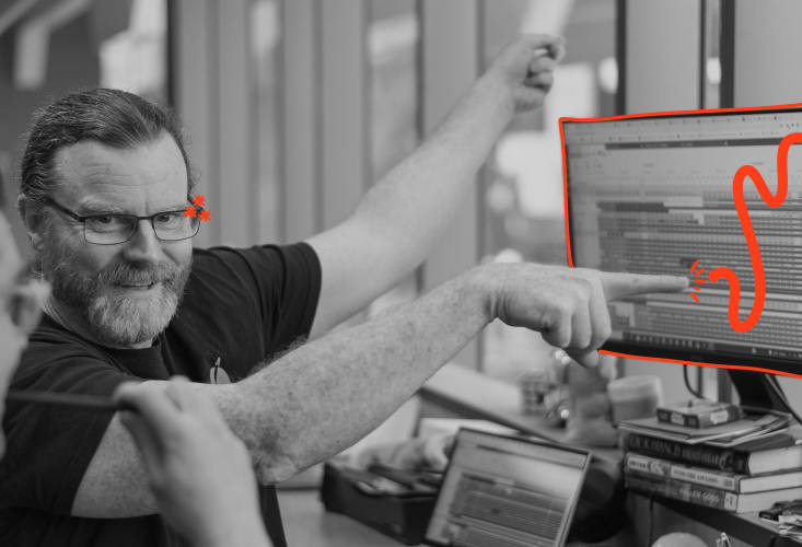 Jidoka blog image featuring two developers in a lively discussion. One is pointing towards a computer screen with a playful orange doodle overlay, symbolising a focus on continuous improvement and problem-solving within the Jidoka framework.