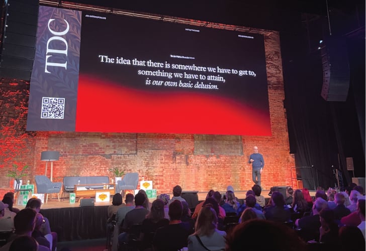 A speaker on stage talkg to a crowd
