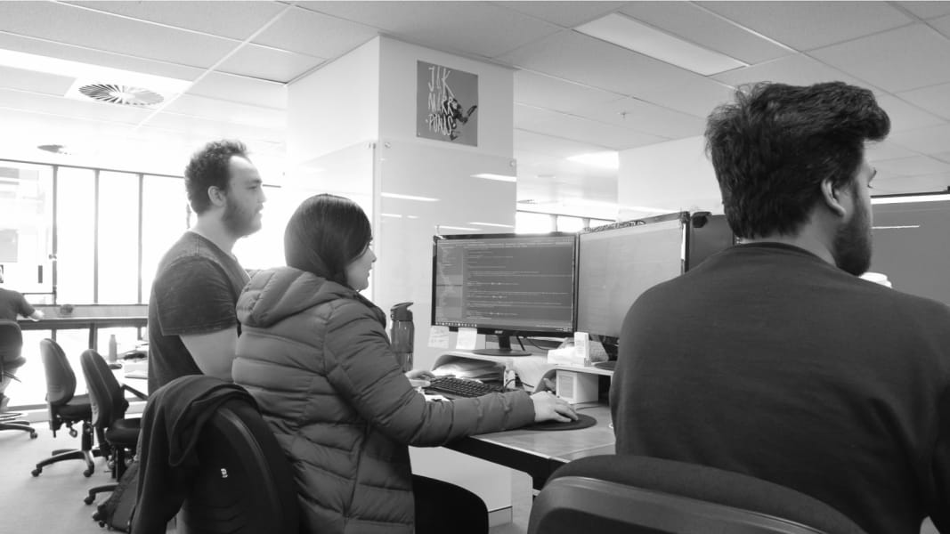 A photo of three people looking at computer screens